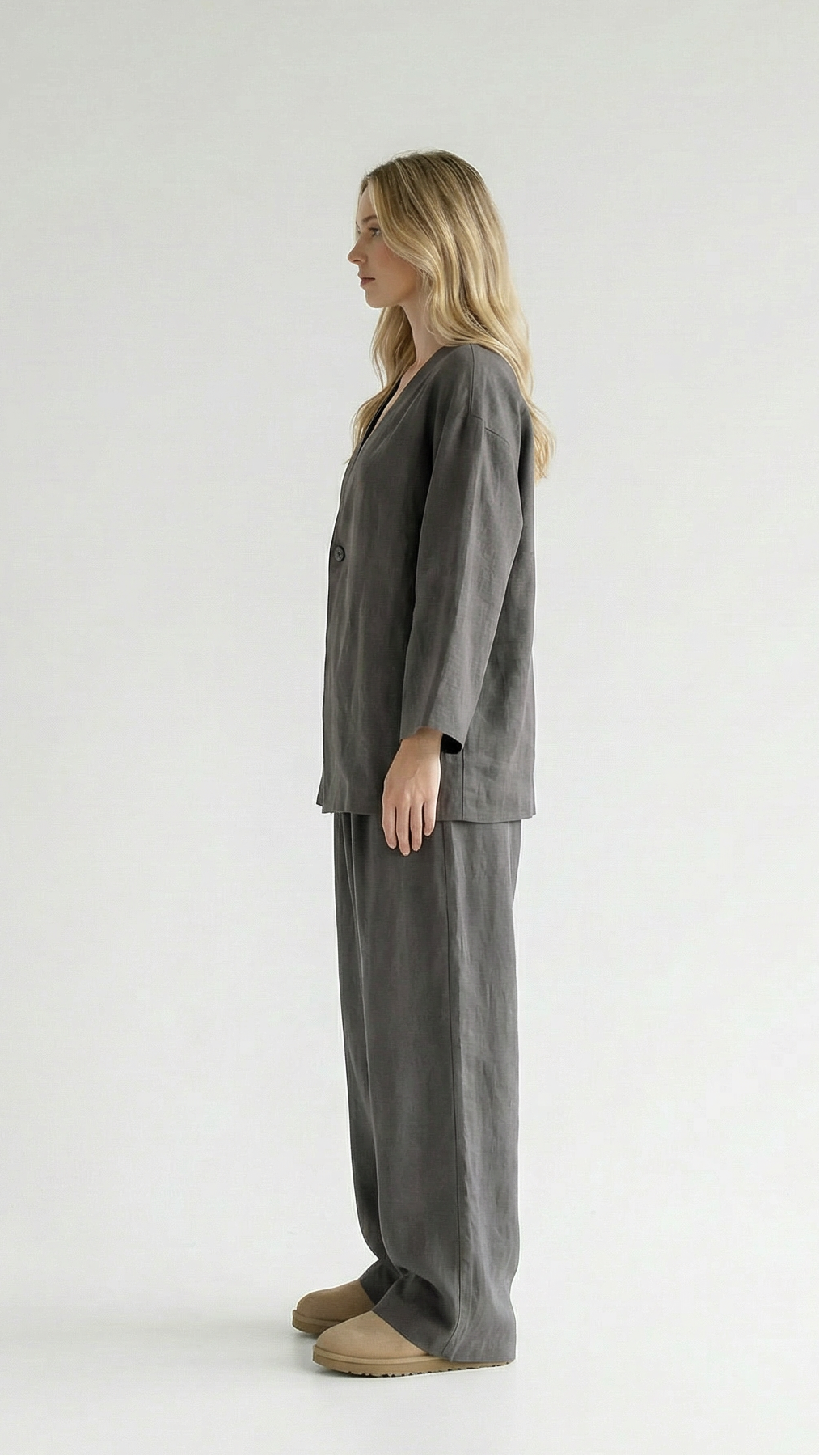 Woman wearing a gray outfit standing against a white background