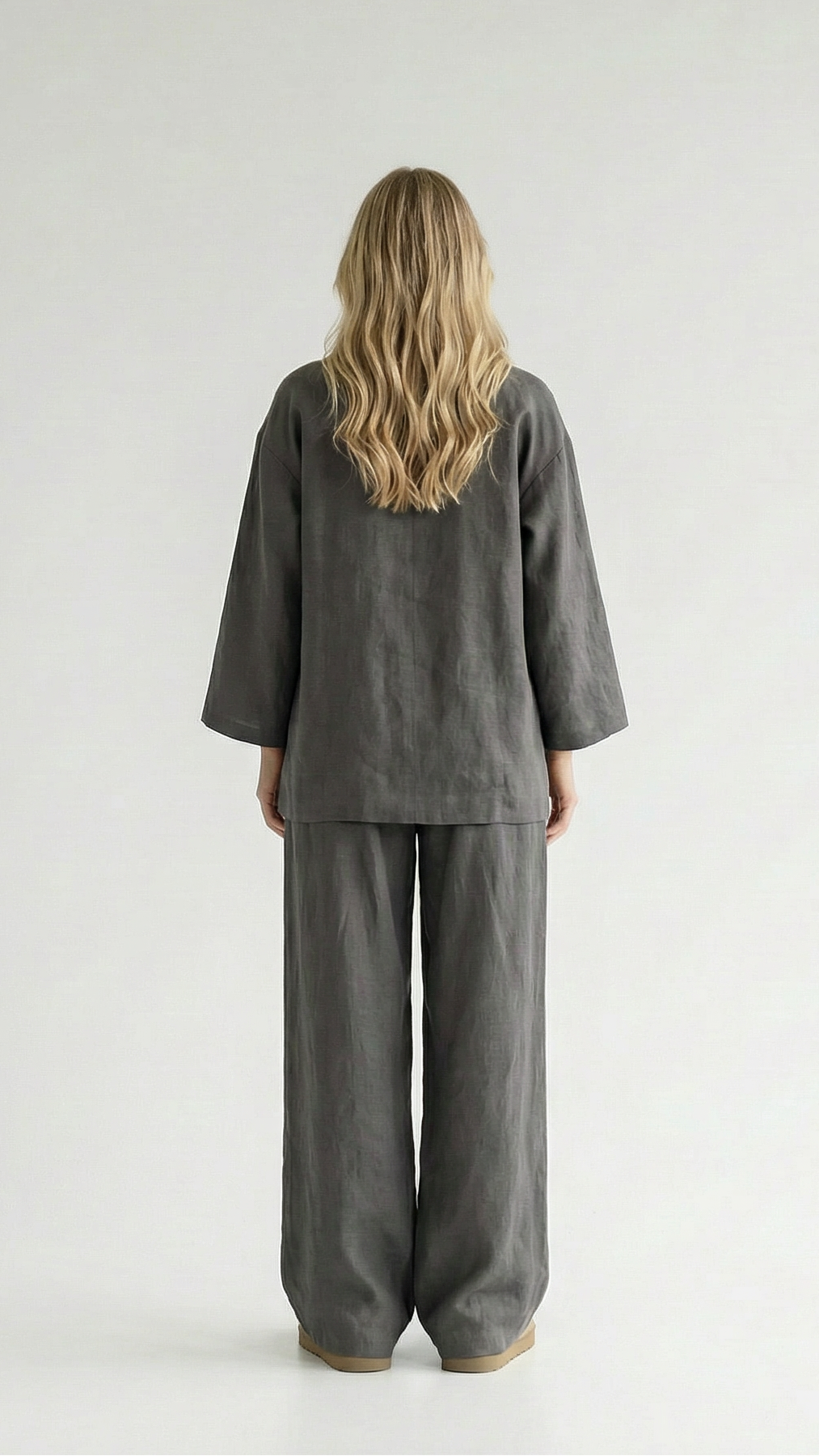 Person wearing a gray outfit standing against a white background