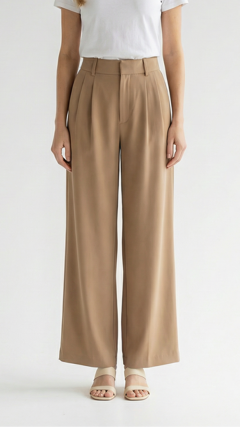 Woman wearing a white t-shirt and beige wide-leg pants on a plain background